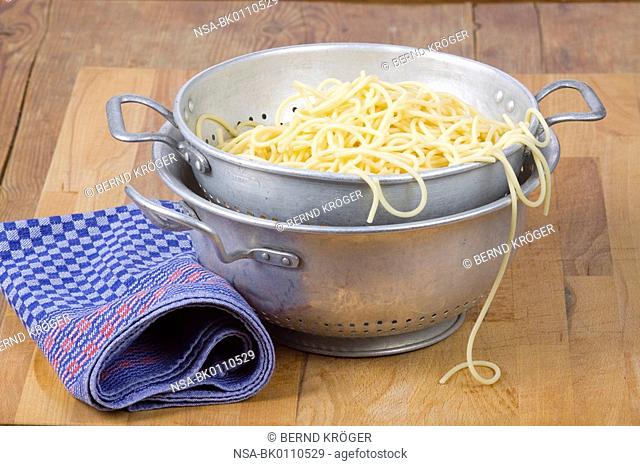 Spaghetti in a tin plate sieve dripping