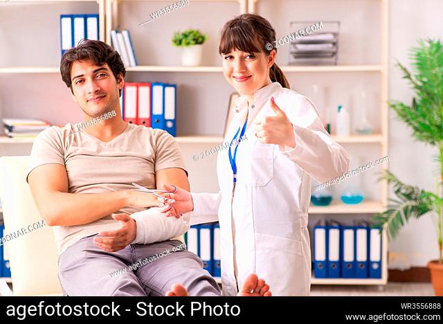 Young man with bandaged arm visiting female doctor traumatologist