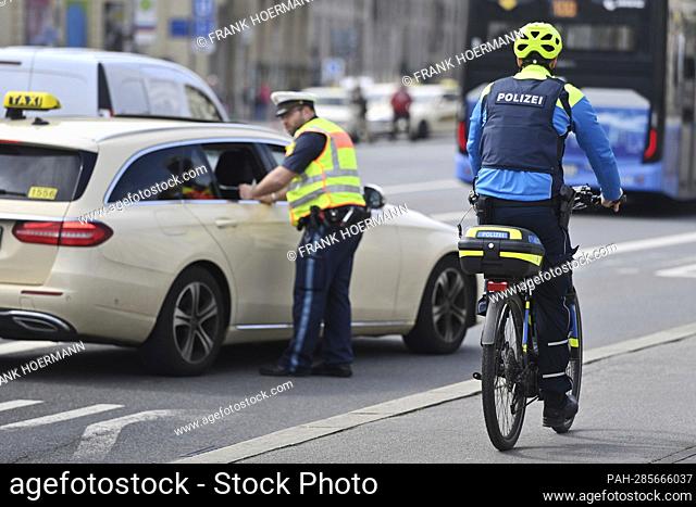 Nationwide day of action ""Driveability at a glance"" on May 5th, 2022 in Munich. A traffic cop controls a taxi driver, taxi while a bicycle cop drives past on...