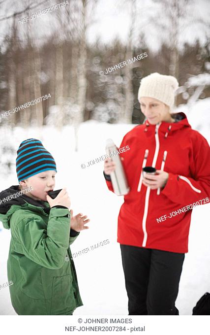 Boy having hot drink in forest