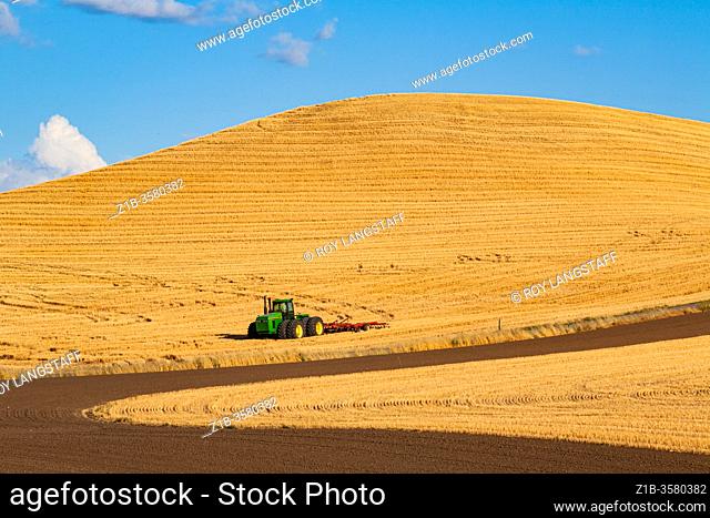 Large tractor parked in a recently harvested field of grain in the Palouse region of eastern Washington State USA