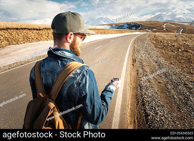 Hipster man using a compass on a snowy mountain