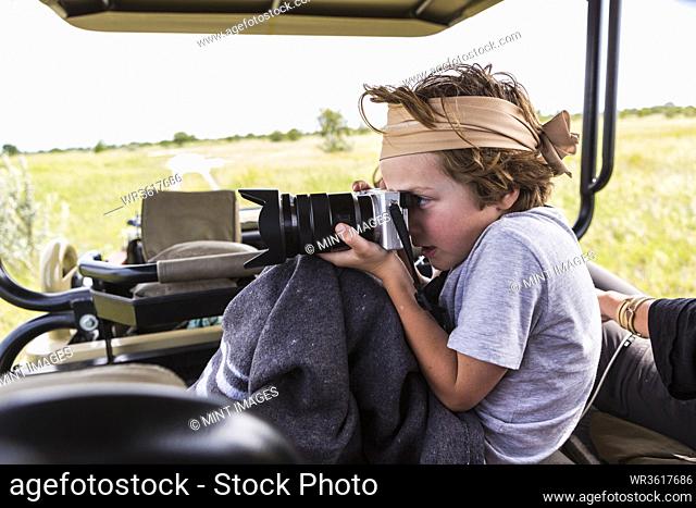 6 year old boy taking pictures from safari vehicle, Botswana