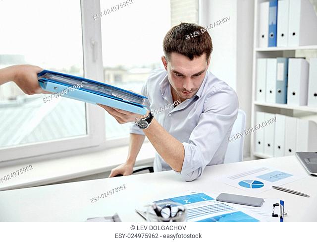 business, people and paperwork concept - businessman taking folder with papers from secretary in office