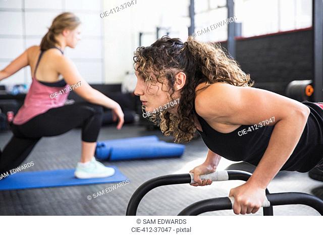 Determined young woman doing push-ups with equipment in gym