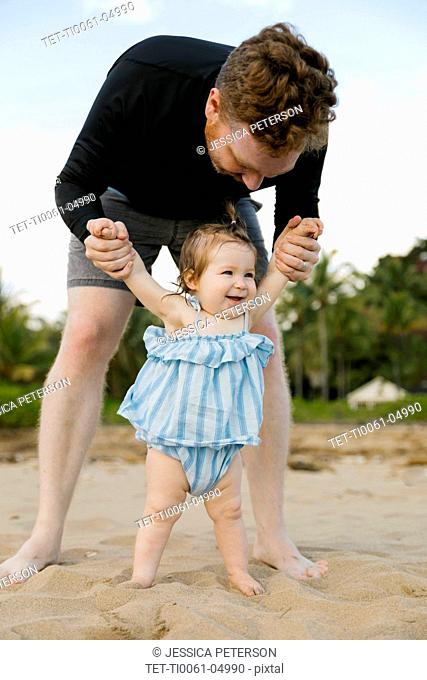 Man playing with baby daughter on beach