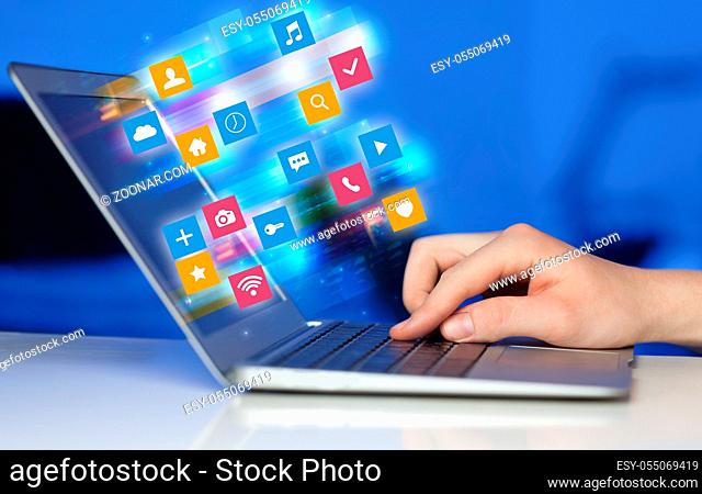 Hand using laptop with colorful fast moving application icons and symbols concept