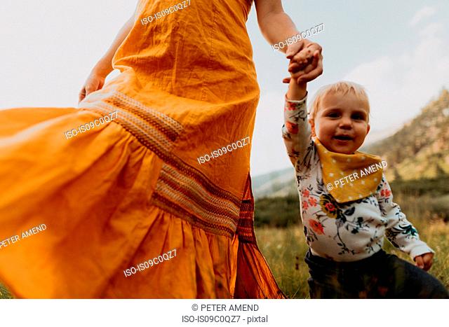 Mother in maxi dress walking with toddler daughter in rural valley, cropped, Mineral King, California, USA