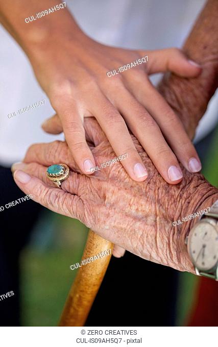 Close up of care assistants hand reassuring senior woman