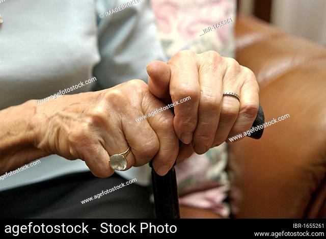 Hands of an elderly woman holding a walking stick