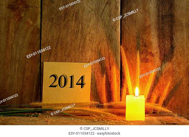 Still life with 2014 wrote on notepad and candle light on wooden background