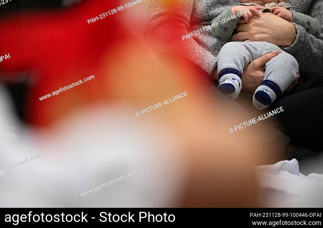 SYMBOL - 24 November 2023, Baden-Württemberg, Stuttgart: A father holds his child on his lap during an infant handling course