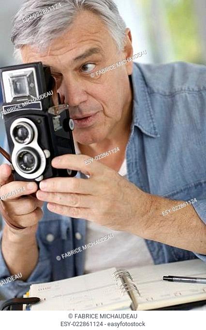 Senior photographer holding vintage camera