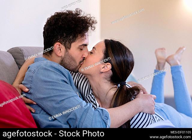 Girlfriend and boyfriend kissing on sofa in living room at home