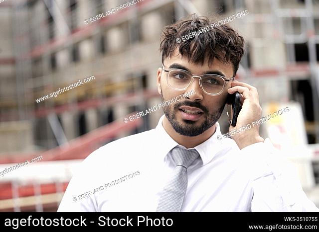 Businessman on building site, talking on phone