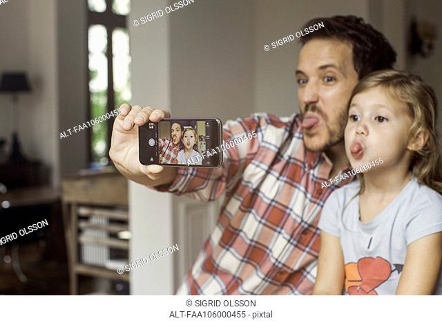 Father and daughter making funny faces selfie