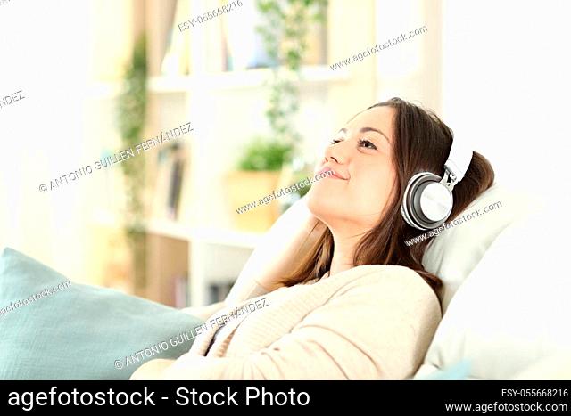 Satisfied woman relaxing sitting on a sofa listening to music at home