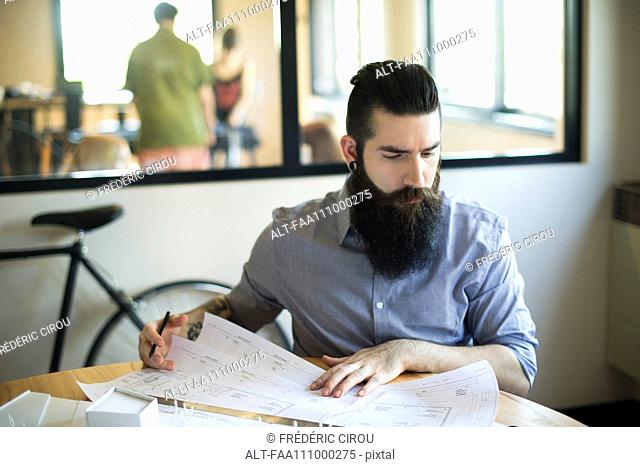 Architect looking at blueprints in office