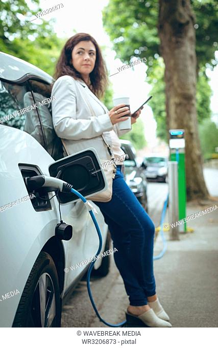 Businesswoman charging electric car at charging station