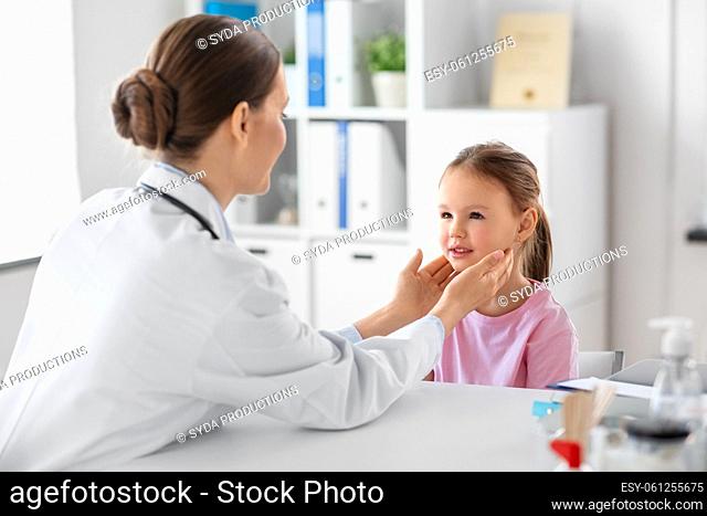doctor checking girl patient's tonsils at clinic