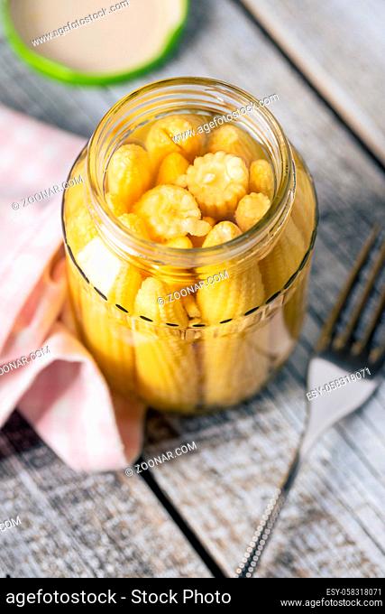 Pickled young baby corn cobs in a jar