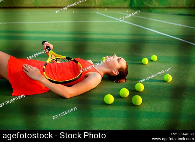 Tired female tennis player with racket lies on outdoor court. Active healthy lifestyle, sport game competition, hard fitness training