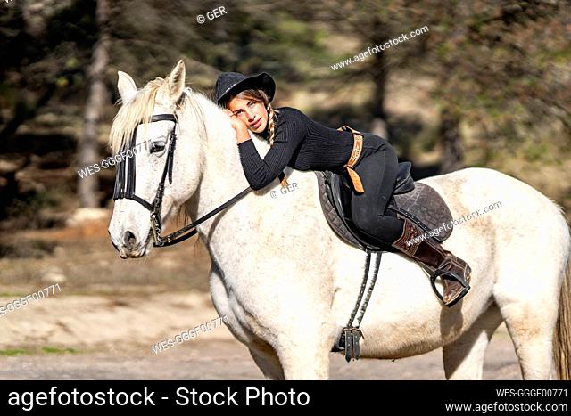 Portrait of woman horseback riding in paddock