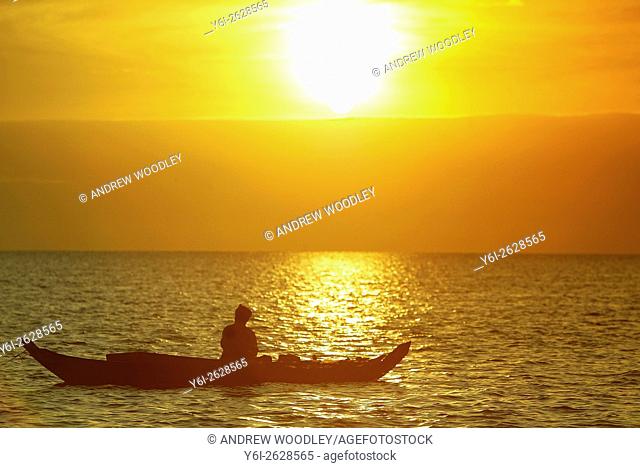Fisherman in small boat sunrise Lake Tonle Sap near Siem Reap Cambodia