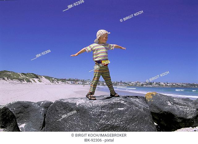 Little boy, four-year-old is standing on a rock at the beach, South Africa