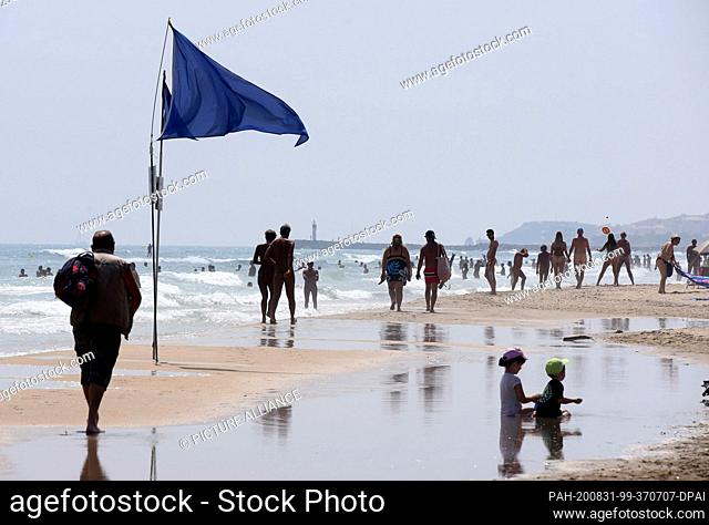 13 August 2020, France, Cap d'Agade: Blue flags show the beginning of the nudist beach of Cap de Agde on the Mediterranean beach of Les Mediterranees in the...