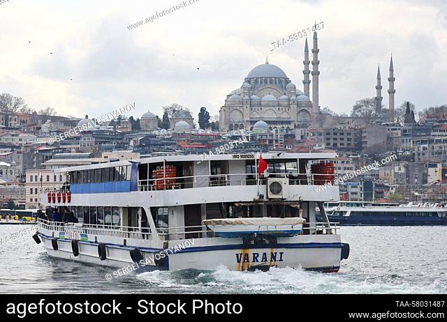 TURKEY, ISTANBUL - MARCH 23, 2023: A ferry carries passengers across the Bosphorus Strait, with the Suleymaniye Mosque in the background