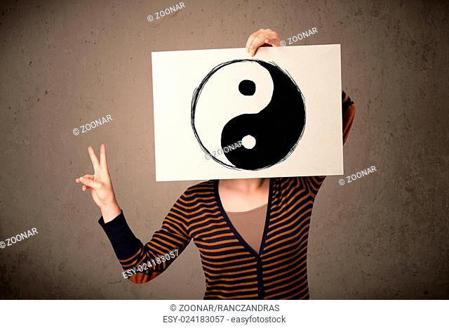Woman holding a paper with a yin-yang on it in front of her head