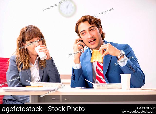 Two colleagues having lunch break at workplace