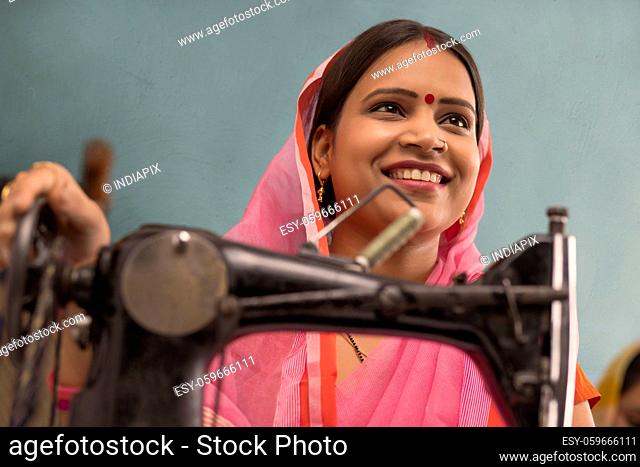 A woman grinning with a sewing machine