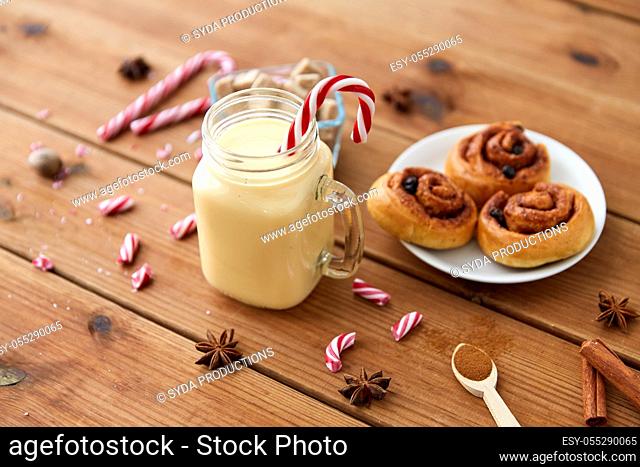 eggnog with candy cane in mug and cinnamon buns