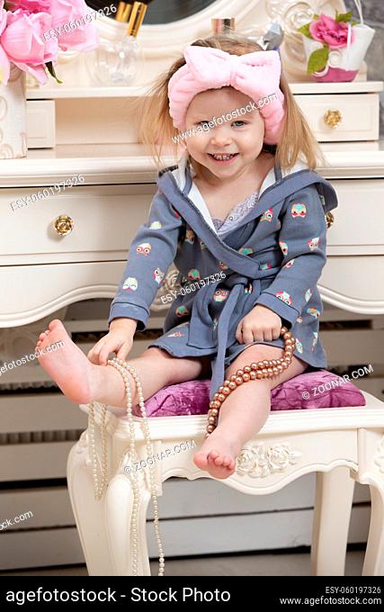 Two-year-old girl. Little girl with beads at the dressing table. Party preparation