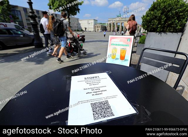 11 June 2021, Berlin: On the tables of restaurants, like here at the Brandenburg Gate, there are signs for visitors indicating that guests must first register...