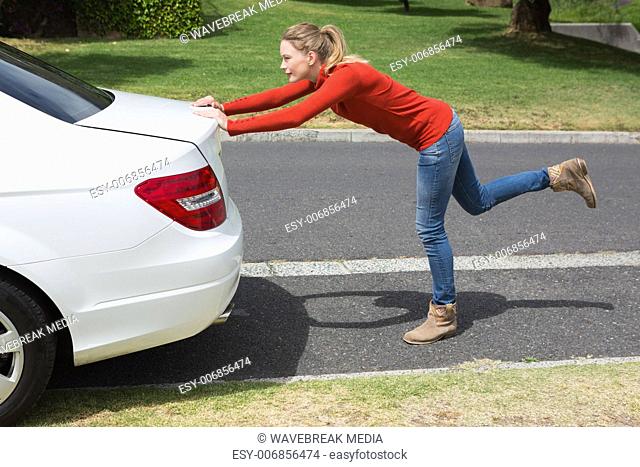 Young woman pushing her broken down car