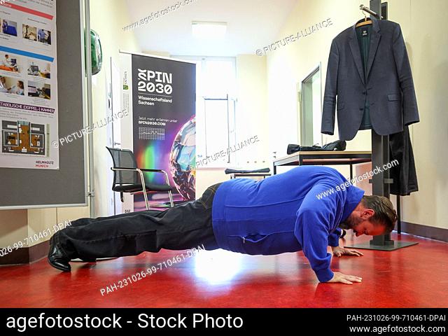 26 October 2023, Saxony, Leipzig: Sebastian Gemkow (CDU), Saxony's Minister of Science, does push-ups in a suit that makes morbid obesity tangible at the...