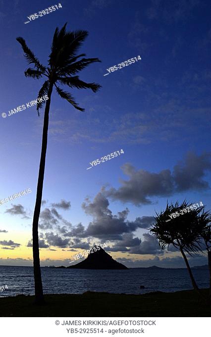 The sun risers behind Mokoli'i Island, also known as Chinaman's Hat, off the coast of Oahu, Hawaii