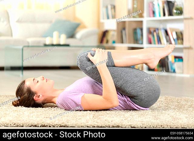 Profile of a concentrated woman doing yoga exercise on the floor at home