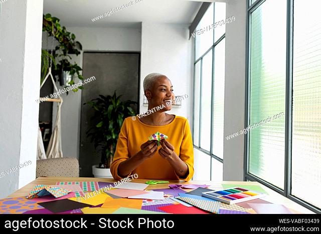 Origami artist sitting in studio working with colorful paper