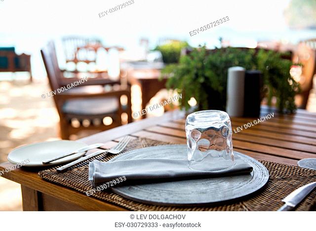 leisure, travel and tourism concept - served table at open-air restaurant on beach