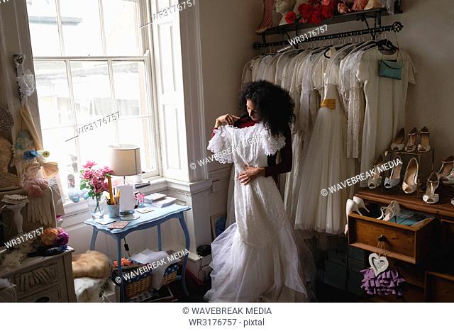 Young bride trying wedding dress from clothes hanger