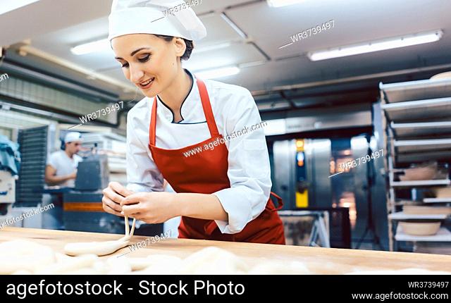 Baker woman forming pretzels and bread, medium shot