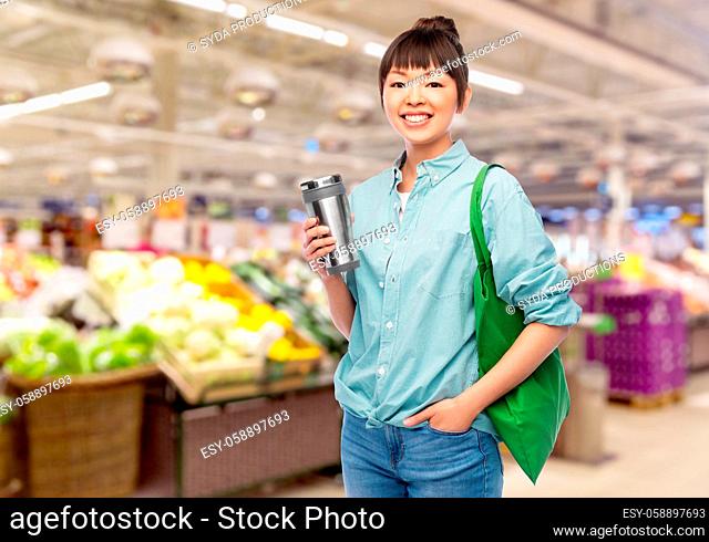 woman with tumbler and reusable food shopping bag