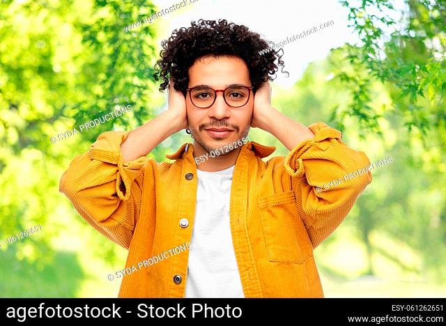 man closing ears by hands on natural background
