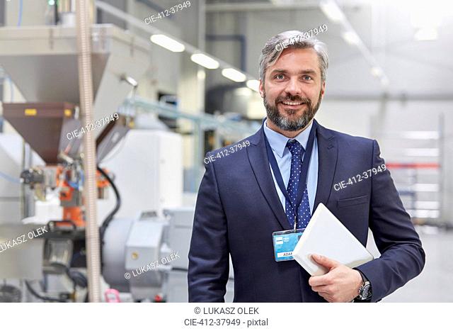 Portrait smiling, confident businessman with digital tablet in fiber optics factory