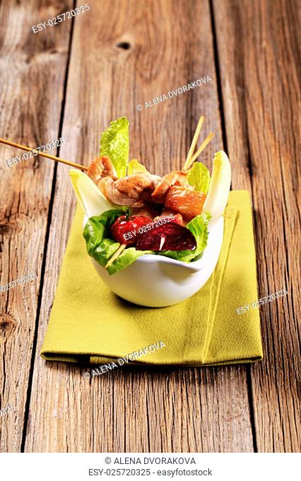 Chicken kebabs on sticks and fresh lettuce