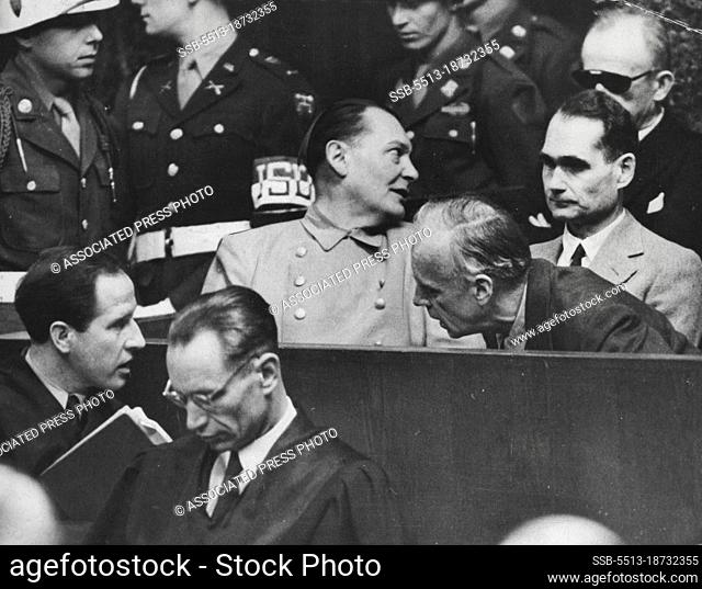 Nazi war criminals whisper in the dock at Nuremberg. Joachim von Ribbentrop leans in front of Rudolf Hess to confer with his lawyer (lower left)